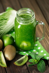 Blended green smoothie with ingredients on wooden table selective focus