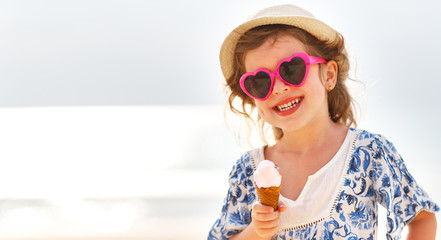 Happy little girl eating ice cream on beach