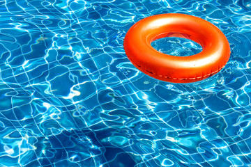 Orange pool float, ring floating in a refreshing blue swimming pool