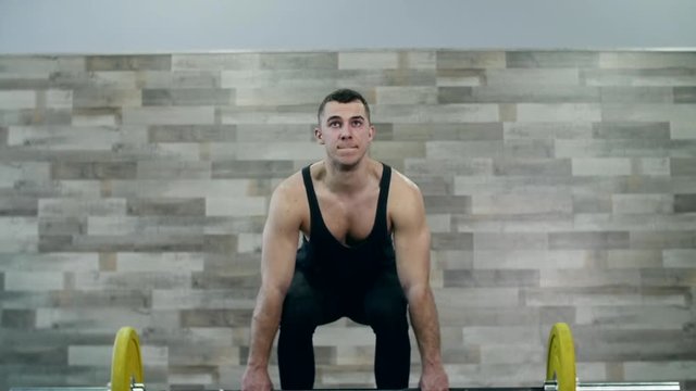 Medium shot slow mo tilt-down tilt-up men exercising and lifting weights female bodybuilder champion athlete doing power clean in cross fit gym