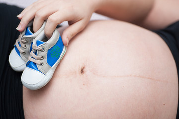 baby shoes on mother's tummy