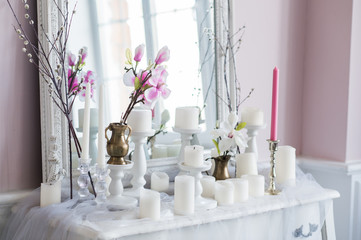 Shabby chic home design. Beautiful decoration table with a candles, flowers in front of a mirror