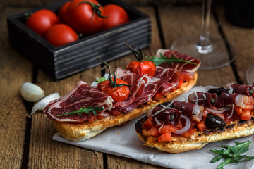 closeup shot of an bruschetta with tomatoes salsa, parma, arugula and olives, close view