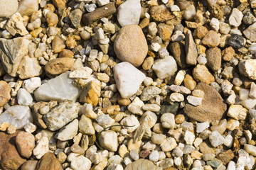 Texture with lot of pebble stone in sunlight, stone background