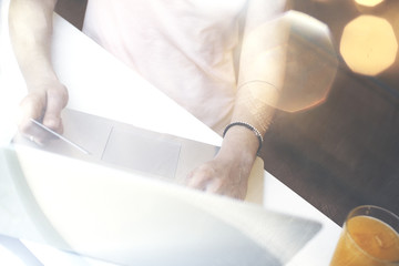 Woman is sitting in cafe with credit card in hand doing online payments on modern laptop