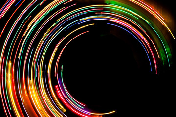 Abstract rotating neon lights texture with black empty copy space inside.