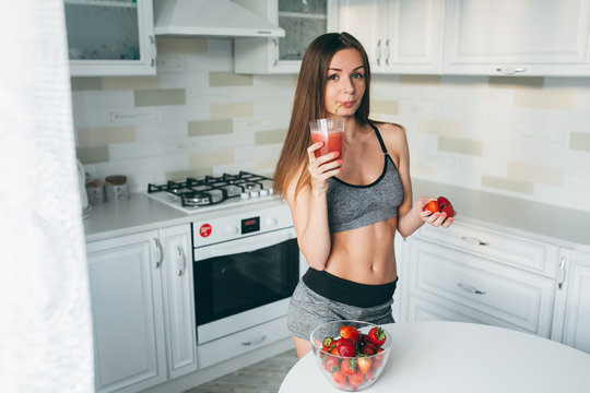 Girl drinking strawberry smoothie on the kitchen.