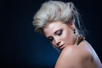 Beautiful blond female fashion model photographed in a dark studio