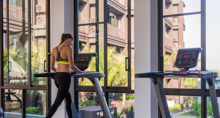 Woman running on the treadmill in the gym with a great poolside view