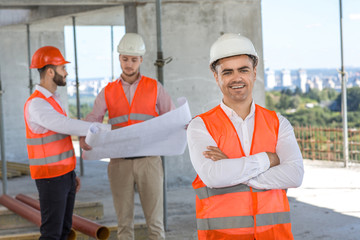 Young engineer at the construction site with his colleagues