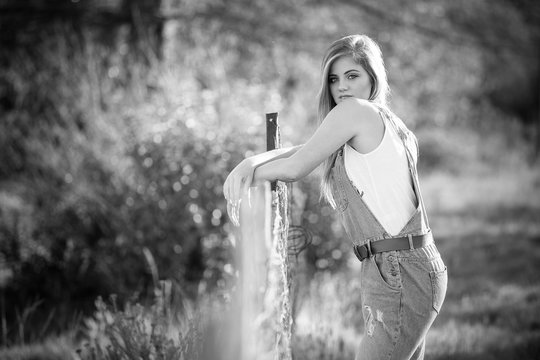 Senior photo of a young woman on a farm wearing farm style clothing