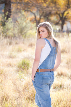 Senior photo of a young woman on a farm wearing farm style clothing