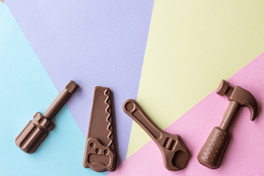 horizontal Easter image of chocolate hand tools spread over a background of purple and yellow blue and pink