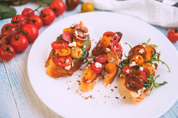 Bruschetta with cheese, basil, arugula and cherry tomatoes