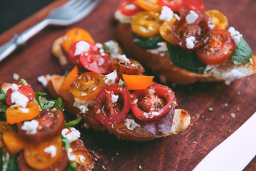 Bruschetta with cheese, basil, arugula and cherry tomatoes