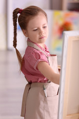 Cute little artist painting picture in studio