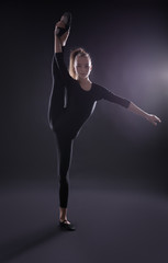 Obraz premium Young girl doing gymnastics on dark background