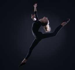 Young girl doing gymnastics on dark background