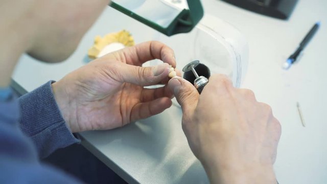 Closeup of grinding teeth crowns with instruments in dental lab in 4K