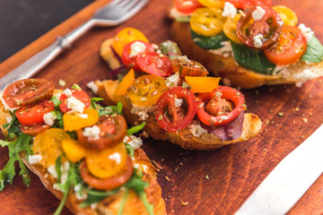 Bruschetta with cheese, basil, arugula and cherry tomatoes