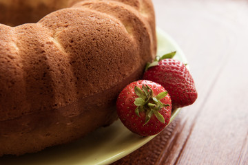 Baked cupcakes and fresh strawberries on the plate on brown background