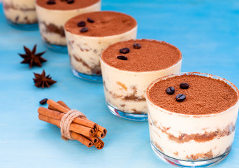 luxurious dessert Tiramisu in a glass on a blue background decorated with mint