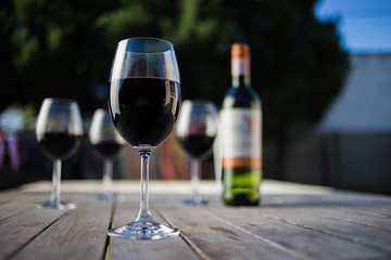 Close up image of wine being poured into a glass on a wooden table outside with natural light