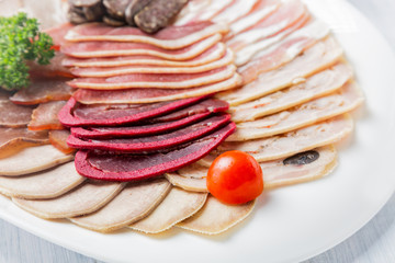 Meat plate with delicious pieces of sliced ham, cherry tomatoes and meat. Close up with selective focus