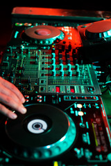 DJ playing music in night club party. Turntable equipment in dark red