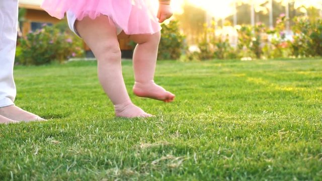 Baby girl doing first steps with mothers help