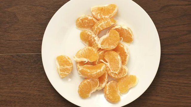 Overhead timelapse of an anonymous couple eating a healthy natural snack of Mandarin Orange segments off of a white plate.