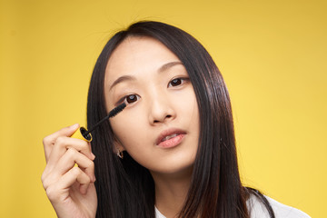 mascara in the hand of a woman on a yellow background