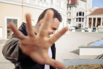 The man on the street not really wants that he was removed and as though removes the camera a hand. He smiles and laughs. It seems, he just was confused. On it a black jacket.