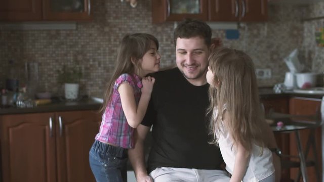 Two little daughters run up to their dad give him hugs and kisses. Single father with his children. slow motion