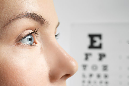 Young woman on eyesight test chart background