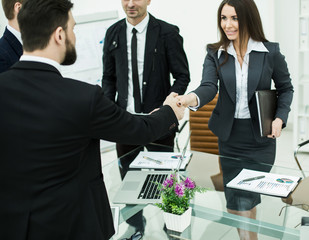 handshake business partners at the meeting near the desktop in a modern office