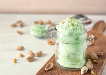 Tasty pistachio ice cream in jar on wooden board