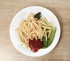 the fries, sauce and salad on plate in the wooden background