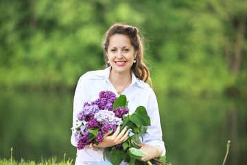 portrait of happy pregnant woman with bouquet of lilacs