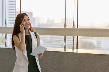 Fototapeta premium Asian Businesswomen holding the tablet and calling the phone with conference Meeting In the modern creative Office, business communication concept
