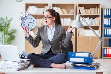 Businesswoman with alarm clock in office