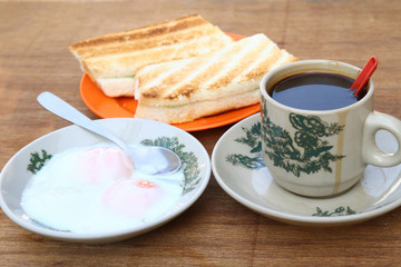 Breakfast set of half boiled eggs, toast and coffee, popular meal in Malaysian and Singaporean coffeeshops
