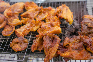 Roasting chicken, grilled spiced chicken stab in wood on a grate.