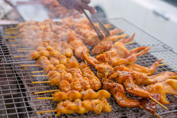 Roasting chicken, grilled spiced chicken stab in wood on a grate.