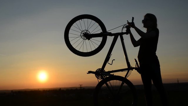 Silhouette of a girl with bicycle in the sunset.