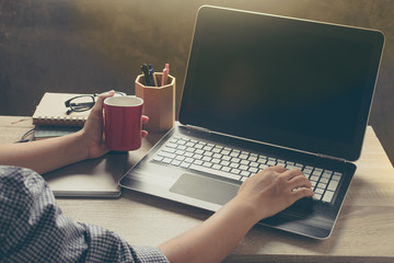 Workspace with girl's hands, laptop and coffee cup in vintage mood with film grain