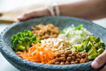 Nice image of a woman serving fresh salad in a buddha bowl.