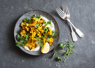 Roasted turmeric cauliflower with greek yogurt dressing. Delicious healthy snack on a dark...