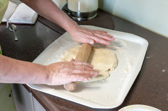 Woman rolls dough for cookie with a rolling pin