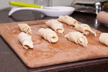 Curd croissants ready for baking on a wooden board